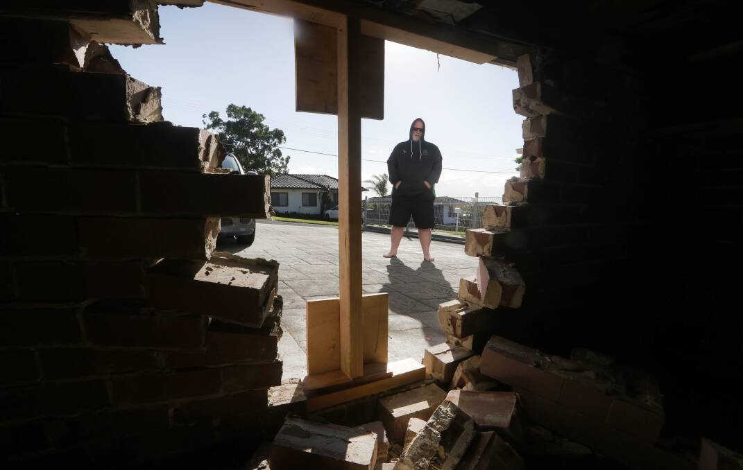 Adam Thomson looking at the large hole an Australia Post van left when it smashed into his Barrack Heights home on April 11, 2024. Picture by Sylvia Liber